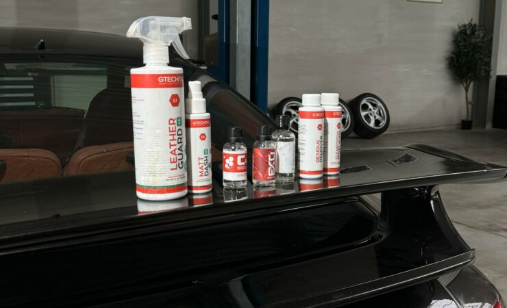 Produits de traitement céramique Gtechniq posés sur l'aileron d'une Porsche 911 dans un atelier de detailing.